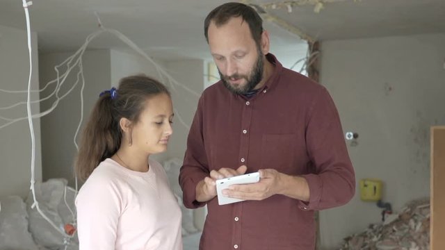 Father and daughter working talking over project on tablet at their new apartment
