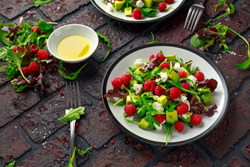 Fresh Tasty Raspberry salad with avocado, green vegetables, nuts, feta cheese, olive oil and herbs. healthy food.