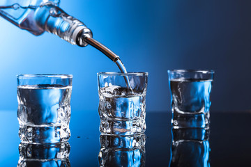 Vodka pouring from the bottle into  glass in a bar.