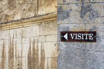 Sign on the wall of the cathedral in Viviers that indicates the direction of the visitors