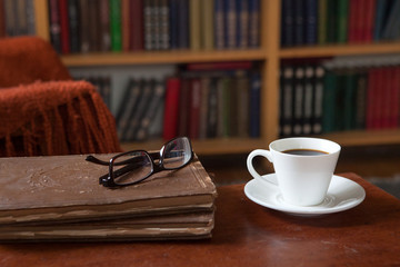 Sweet moments of relaxation with books and a cup of coffee. Vintage books, glasses, chair, library