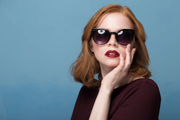 Close up shot of stylish young woman in sunglasses smiling against blue background. Beautiful female model with copy space. Spring and summer eyewear collection, fashion, fashion.
