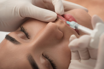 Close up of female lips getting hyaluronic acid injection by beautician