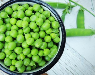 Organic sweet green peas in vintage cup on vintage wooden white background.	