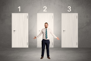 Businessman thinking in front of three doors