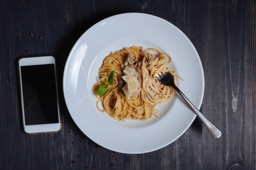 Smart phone lying near spaghetti