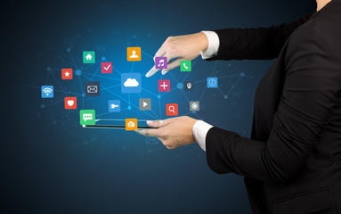 Hand holding tablet and application icons above