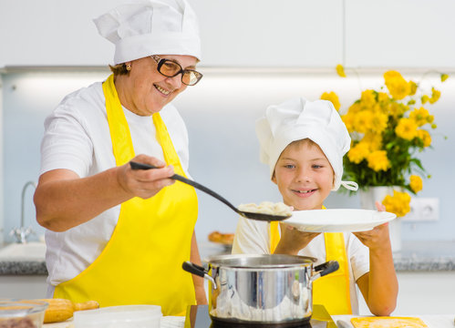 Senior woman  with a happy grandson is cooked in the kitchen of dumplings