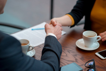It is good job. Close up girl arm shaking hands with partner. They sitting at table. Profession...