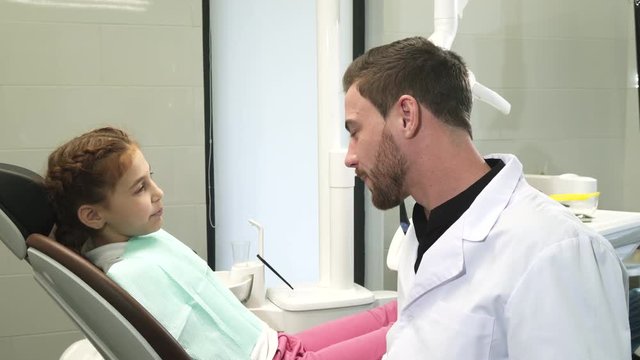 Lovely dentist talking with his young patient