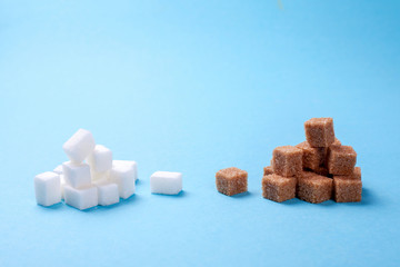 White and brown sugar cane sugar cubes on a blue background. Copy space for text