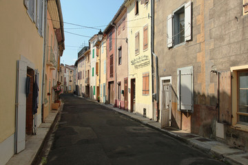 Fototapeta na wymiar Multi-coloured row of cottages, situated along a deserted village street in the South of France