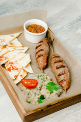 Top view. Grilled beef sausages with chips, mushrooms puree, vegetables, onion, garlic and greens, pepper, tomato sauce, ketchup, chilli on wooden background. Restaurant kitchen