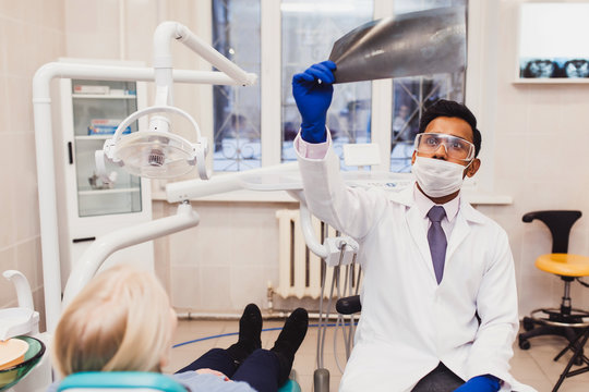 A young Asian dentist treats a girl's teeth and diagnoses a picture. Dentist chair