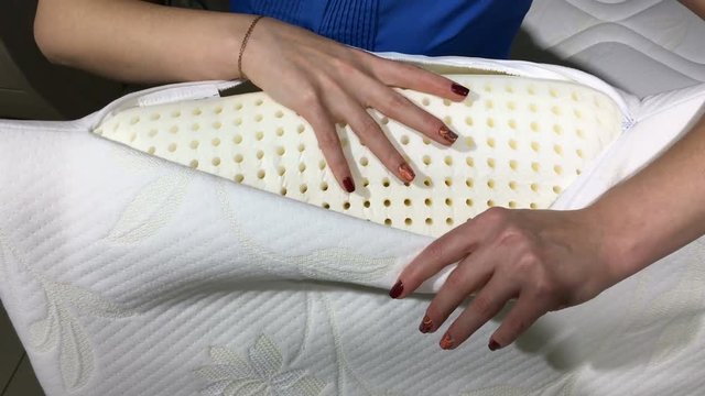 Orthopedic pillow with a memory effect. Hands of the girl squeeze a pillow from memory foam.