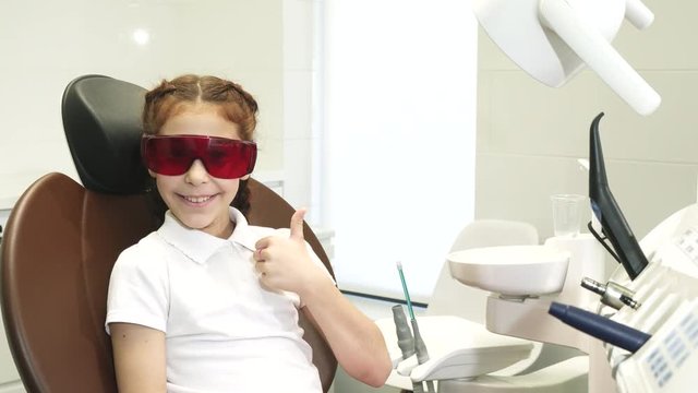 Happy girl at the reception at the dentist shows a thumbs up