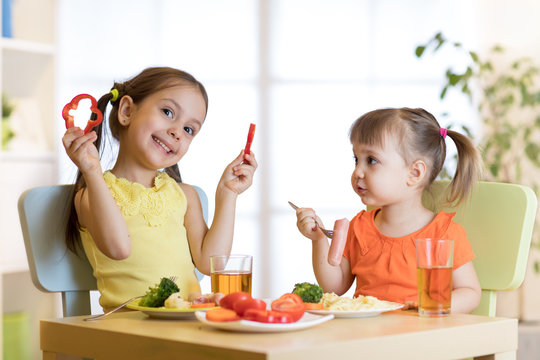 Cute children girls eating healthy food. Kids lunch at home or kindergarten.