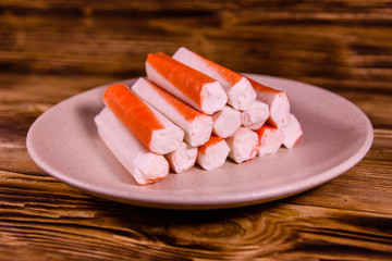 Ceramic plate with crab sticks on wooden table