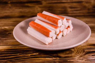 Ceramic plate with crab sticks on wooden table