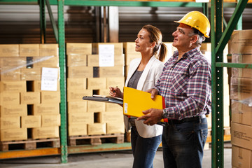 Manager and warehouse worker checking list and inventory on the shelf in storehouse.