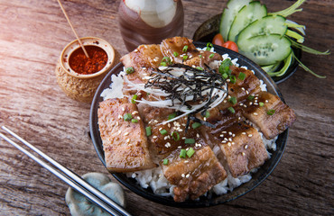 Grilled slice pork with charcoal flame set on rice bowl in Japanese style.