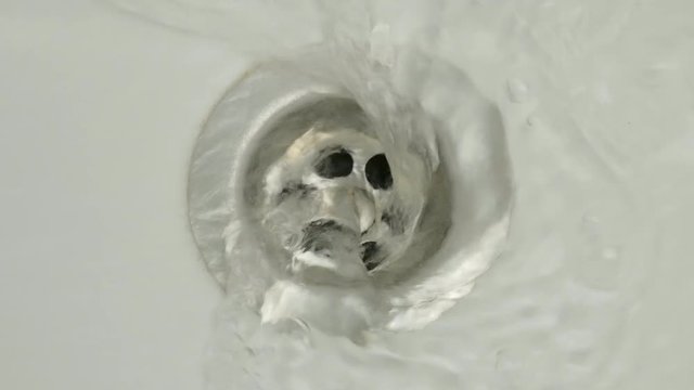 Water flows into the drain hole in the white sink