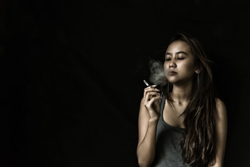 Woman Smoking a Cigarette on Black Background. Portrait  of a beautiful girl, letting out smoke cigarettes. Women addicted smoking. People having problem and smoking cigarette.