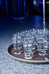 Several shot glasses on silver tray in bar setting