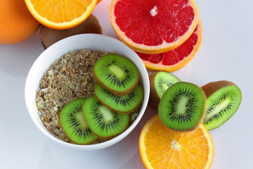 Background with citrus fruit slices with oatmeal bowl on white table
