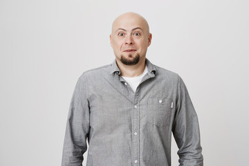 Portrait of bald mature man with beard looking surprised and amazed at camera while standing over white background. Adult wearing casual clothes, stunned. He did not expect to see his friend.