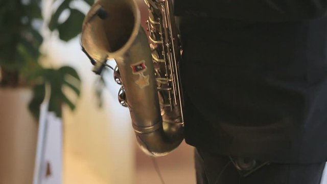 Saxophonist playing on an old saxophone in the room. Live performance. Jazz artist. Microphone