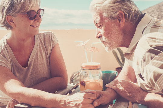 senior couple in love drinking fruit juice on rooftop - Powered by Adobe