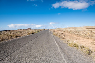 Fototapeta na wymiar Travel on a long road in Fuerteventura with desert at both sides