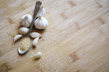 Garlic bulbs, cloves and garlic powder on a wooden background