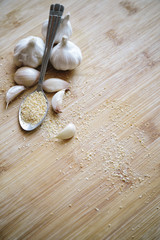 Garlic bulbs, cloves and garlic powder on a wooden background