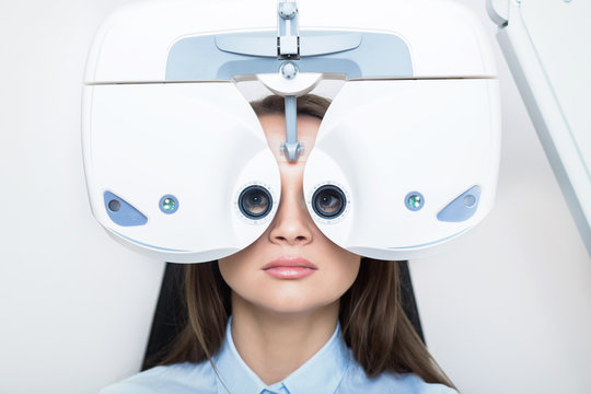 patient woman having her eyes examined with phoropter, face close -up
