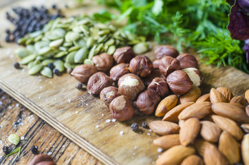 Fresh nuts and spices. Forest nuts, almonds, pepper, salt on a wooden board.