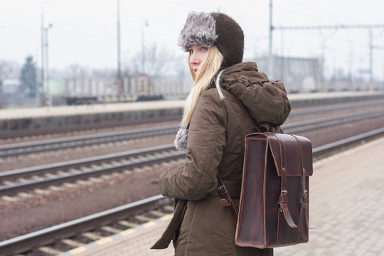 woman traveler with brown leather rucksack waiting train