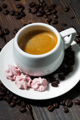 cup of espresso and pink meringues on dark wooden background, vertical top view