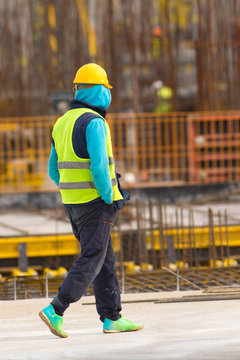 Lazy worker is walking with hands in pockets through the  construction site