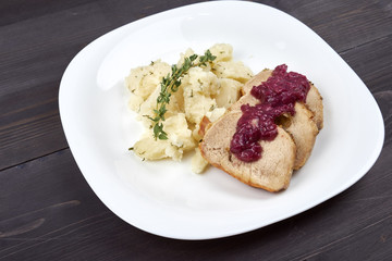 Pieces of meat in sauce with potatoes on a white plate