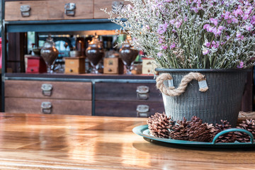 Close up dry Statice flower in pot on wooden table with blurred decorated shelves background