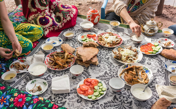 Lots of traditional foods of Tajikistan on a restaurant table, people are eating
