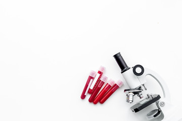 Blood analysis in clinacal lab. Test tubes near microscope on white background top view copy space