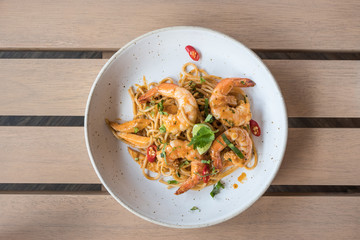 Spicy spaghetti with shrimps on wooden table background