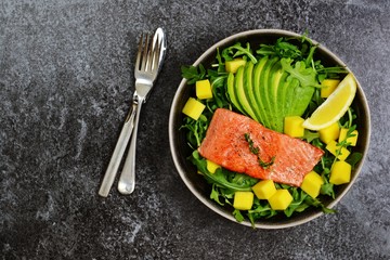 Salmon and mango salad on the dark background. Top view food