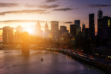 Colorful sunset behind the Brooklyn Bridge and skyscrapers of the Manhattan skyline in New York City