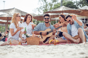 Happy people eating pizza and have fun on the beach.