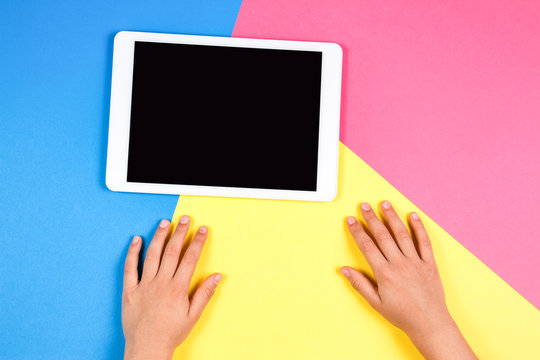 Kid hands with tablet computer on colorful background