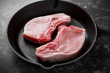 Raw Pork Loin chops in rustic skillet, pan.